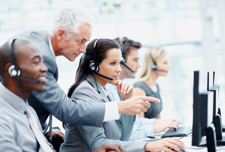Side view of a smart senior manager and his team working in a call center